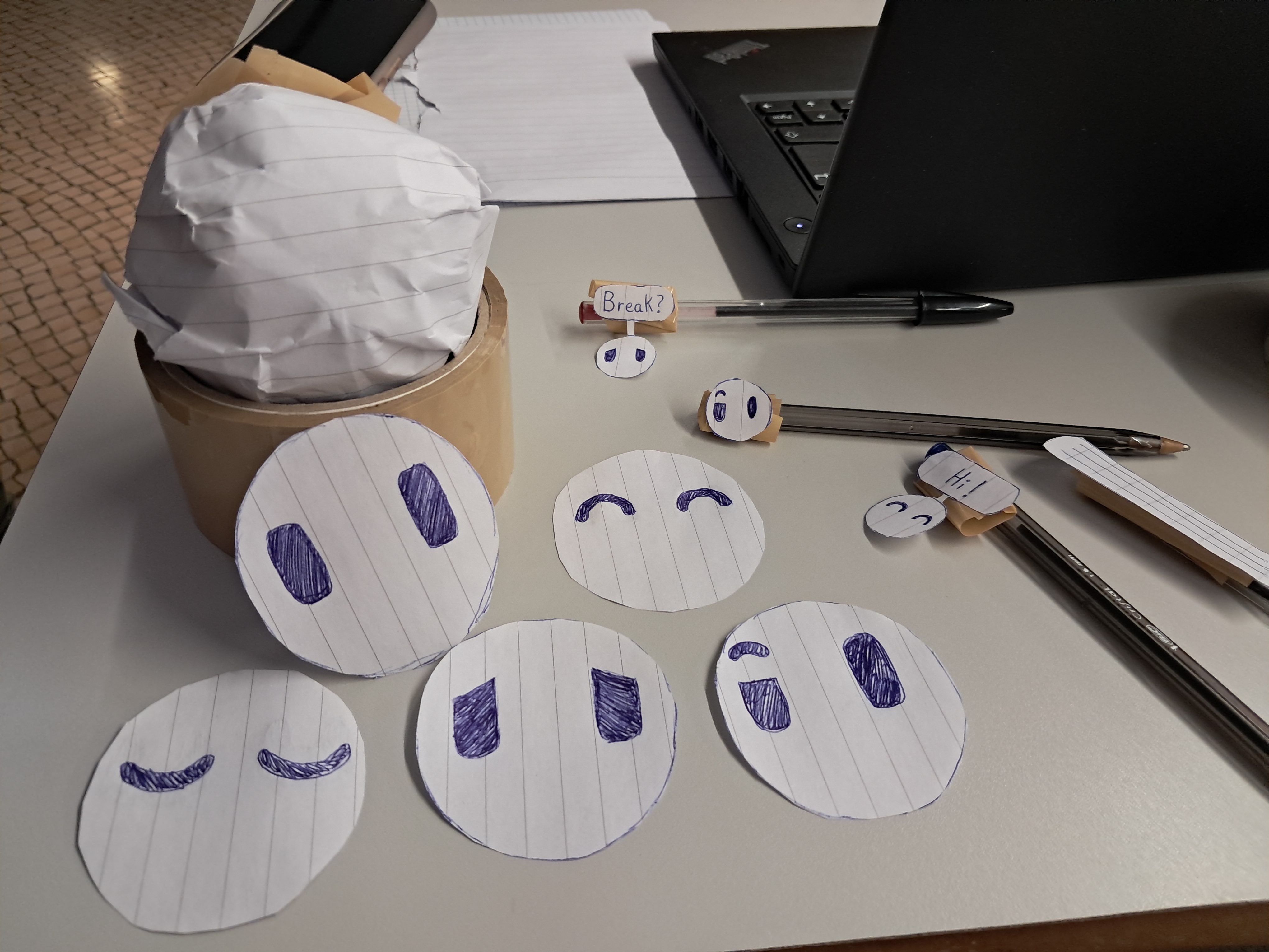 Paper prototype of Mylow's robot body, expressive faces and notification texts.